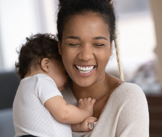 Smiling african American mom cuddle with small baby